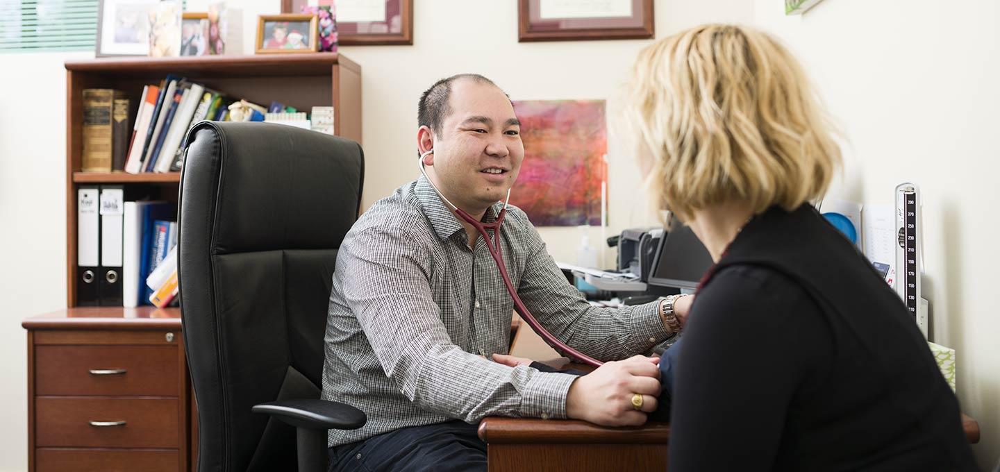 A clinician taking a patient's blood pressure in a consulting room