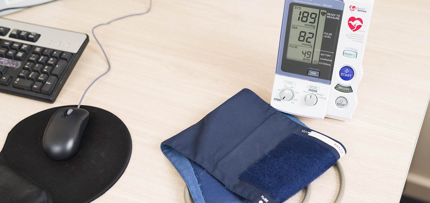 A blood pressure monitor and cuff on a desk.